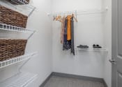 Thumbnail 26 of 37 - a walk in closet with white walls and shelves and a closet door open with clothes