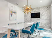 Thumbnail 6 of 29 - A modern conference room with a white table and blue chairs.