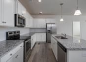 Thumbnail 9 of 27 - a kitchen with white cabinets and gray countertops