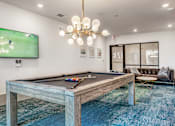 Thumbnail 10 of 29 - A pool table with a TV showing a game in the background.