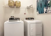 Thumbnail 23 of 29 - A white washing machine and dryer in a small laundry room.
