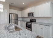 Thumbnail 13 of 23 - a kitchen with white cabinets and granite countertops