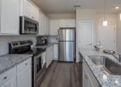 Thumbnail 12 of 23 - a kitchen with white cabinets and gray countertops