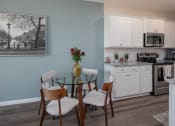 Thumbnail 4 of 23 - a dining area with a glass table and four chairs and a kitchen in the background