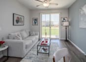 Thumbnail 6 of 23 - a living room with a large window and a ceiling fan