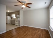 Thumbnail 16 of 26 - a bedroom with a ceiling fan and a kitchen in the background