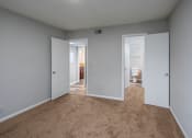 Thumbnail 13 of 25 - a bedroom with two doors and a bathroom in the background