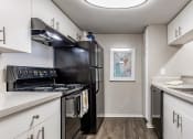 Thumbnail 8 of 34 - an apartment kitchen with black appliances and white cabinets at L'Estancia, Sarasota, FL