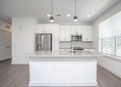 Thumbnail 49 of 50 - a white kitchen with a large island and a stainless steel refrigerator