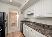 Thumbnail 15 of 35 - A kitchen with white cabinets and a black fridge.