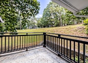 Thumbnail 20 of 35 - A balcony with a black railing overlooks a grassy area.