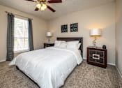 Thumbnail 12 of 30 - A bedroom with a large bed and a ceiling fan.