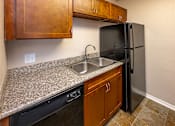 Thumbnail 14 of 30 - A kitchen with a black refrigerator and brown cabinets.