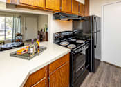 Thumbnail 7 of 30 - A kitchen with a black stove top oven and a black refrigerator.
