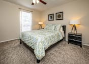 Thumbnail 10 of 30 - A bedroom with a bed, nightstands, and a ceiling fan.