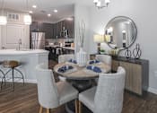 Thumbnail 3 of 41 - A modern dining room with a round mirror and a wooden table.
