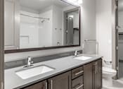 Thumbnail 21 of 36 - A bathroom with a sink, mirror, and toilet.