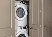 Thumbnail 22 of 36 - A white washing machine is stacked on top of another white washing machine in a cabinet.