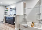 Thumbnail 11 of 35 - 1-Bedroom Luxury Apartments in Altamonte Springs, FL - Nine12 Gateway - Bathroom with Vinyl Plank Flooring, Garden Tub Shower, Large Sink Vanity, and Floating Shelves.