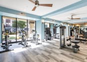 Thumbnail 12 of 35 - Two-Bedroom Luxury Apartments in Altamonte Springs, FL - Nine12 Gateway - Fitness Center with Floor-to-Ceiling Windows, Stationary Bikes, Strength Training Equipment, Ceiling Fans, and Mirror Wall.