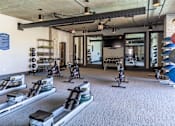 Thumbnail 30 of 46 - a gym with treadmills and other exercise equipment in a building with glass doors