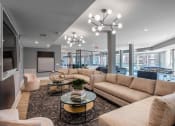 Thumbnail 2 of 32 - Apartments in Mt. Juliet TN - The Enclave - Common Area with Hardwood-Style Flooring, Area Rug, Sectional Couches, Armchairs, Round Glass Coffeetables, Wall-Mounted Television, Foosball and Billiards Tables, and Floor-to-Ceiling Windows
