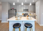 Thumbnail 9 of 32 - 1-Bedroom Apartments in Mt. Juliet, TN - The Enclave at Providence - Kitchen with Hardwood-Style Flooring, Island with Seating, Pendant Lights, Granite Countertops, Stainless Steel Appliances, and Grey Shaker-Style Cabinets.