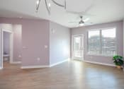Thumbnail 11 of 32 - Mt. Juliet Apartments for Rent - The Enclave - Empty Living Room with Hardwood-Style Flooring, Pink Walls, Ceiling Fan, Window with Blinds, and Door with Access to Balcony/Patio