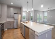 Thumbnail 14 of 32 - Apartments for Rent in Mt. Juliet TN - The Enclave - Kitchen with Hardwood-Style Flooring, Stainless Steel Appliances, Shaker-Style Cabinets, Spacious Kitchen Island with Pendant Lights, and Granite Countertops