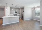 Thumbnail 12 of 32 - an open kitchen and living room with a white island and a stainless steel refrigerator
