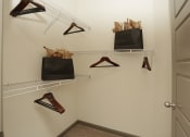 Thumbnail 19 of 36 - a walk in closet with shoe racks and bags