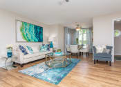 Thumbnail 9 of 18 - Pet-Friendly Apartments in Stockbridge, GA - Avenue 33 - Living Room with Wood-Inspired Plank Flooring, a Dining Area With a Ceiling Fan, and Windows with Blinds.
