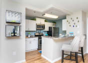 Thumbnail 7 of 18 - an open kitchen and dining area with white cabinets and stainless steel appliances