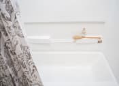 Thumbnail 14 of 16 - a white bathtub with a shower curtain and a soap dispenser on the shelf
