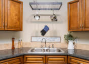 Thumbnail 11 of 31 - a kitchen with a sink and cabinets and a pot rack above it