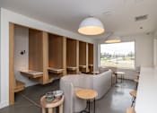 Thumbnail 2 of 15 - a lounge area with tables and chairs and a large window
