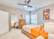Thumbnail 7 of 29 - a bedroom with a bed and a ceiling fan and a mirror