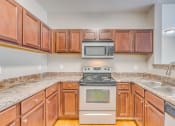 Thumbnail 6 of 29 - a kitchen with wood cabinets and granite counter tops and a stove and microwave