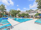 Thumbnail 23 of 36 - A swimming pool surrounded by blue lounge chairs and umbrellas.
