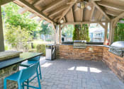 Thumbnail 22 of 38 - a covered outdoor kitchen with a brick wall and a grill