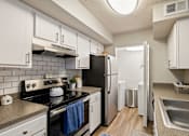 Thumbnail 11 of 30 - A kitchen with white cabinets and a black stove top oven.