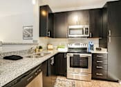 Thumbnail 10 of 30 - A modern kitchen with black cabinets and stainless steel appliances.