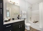 Thumbnail 19 of 30 - A bathroom with a white tub, sink, and toilet.