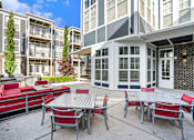 Thumbnail 21 of 30 - A patio with a table and chairs is surrounded by apartment buildings.