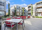 Thumbnail 20 of 30 - A patio with a table and chairs is surrounded by apartment buildings.