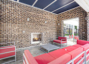 Thumbnail 23 of 30 - A patio with red couches and a brick wall.