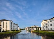 Thumbnail 30 of 31 - A river flows through a residential area with modern buildings on either side.