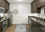 Thumbnail 7 of 32 - A kitchen with brown cabinets and a white door.