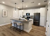 Thumbnail 5 of 11 - A kitchen with a black refrigerator and white cabinets.