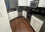 Thumbnail 14 of 39 - a large kitchen with wooden floors and white cabinets